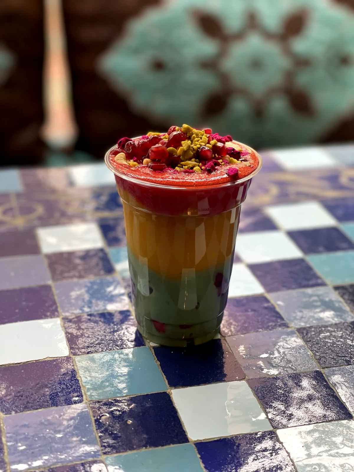 Geschichteter Smoothie mit Granatapfelkernen im To-Go-Becher